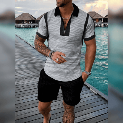 Mann in grauem Poloshirt und schwarzen Shorts auf Holzsteg am Meer, Sommermode, Urlaub.