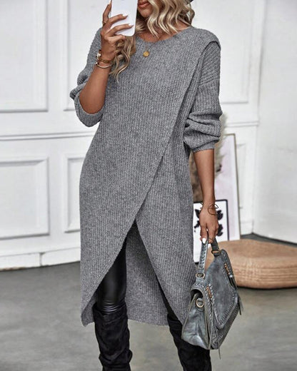 Frau in grauem Strickkleid, Lederhose, Stiefel, hält graue Handtasche, modisch, elegant.