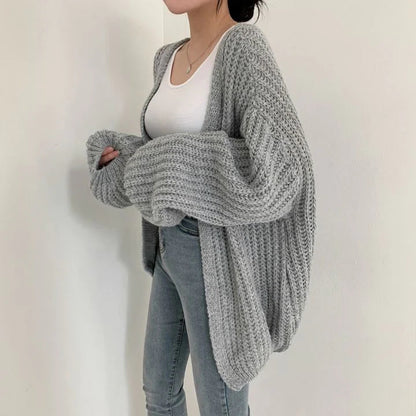 Grauer Damen-Strickcardigan, gemütlich und stilvoll, über weißem Top und Jeans getragen.