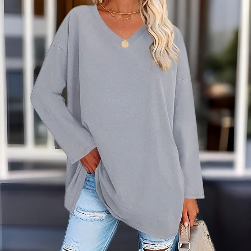 Frau in grauem Oversize-Pullover und zerrissenen Jeans, lässige Mode, eleganter Look.