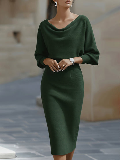 Frontansicht: Model in dunkelgrünem Strickkleid mit lockerem Oberteil, drapiertem Ausschnitt und eng anliegendem Rock mit Taillenbund. 4