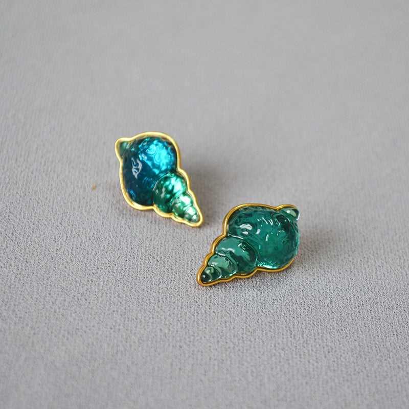 Grüne Muschel-Ohrringe, goldumrandet, auf grauem Hintergrund, Modeschmuck Accessoire.