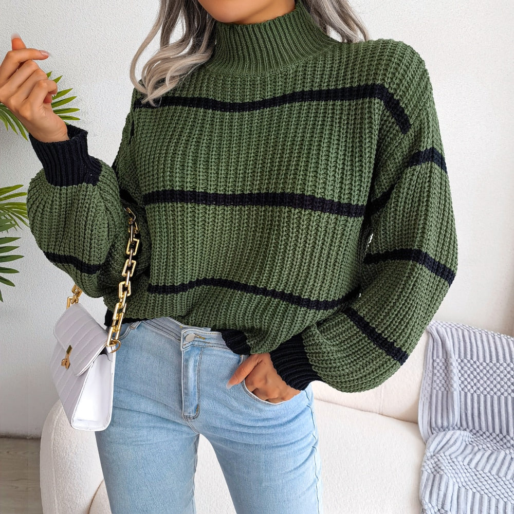 Frau in grünem Strickpullover mit schwarzen Streifen, weiße Handtasche, blaue Jeans.