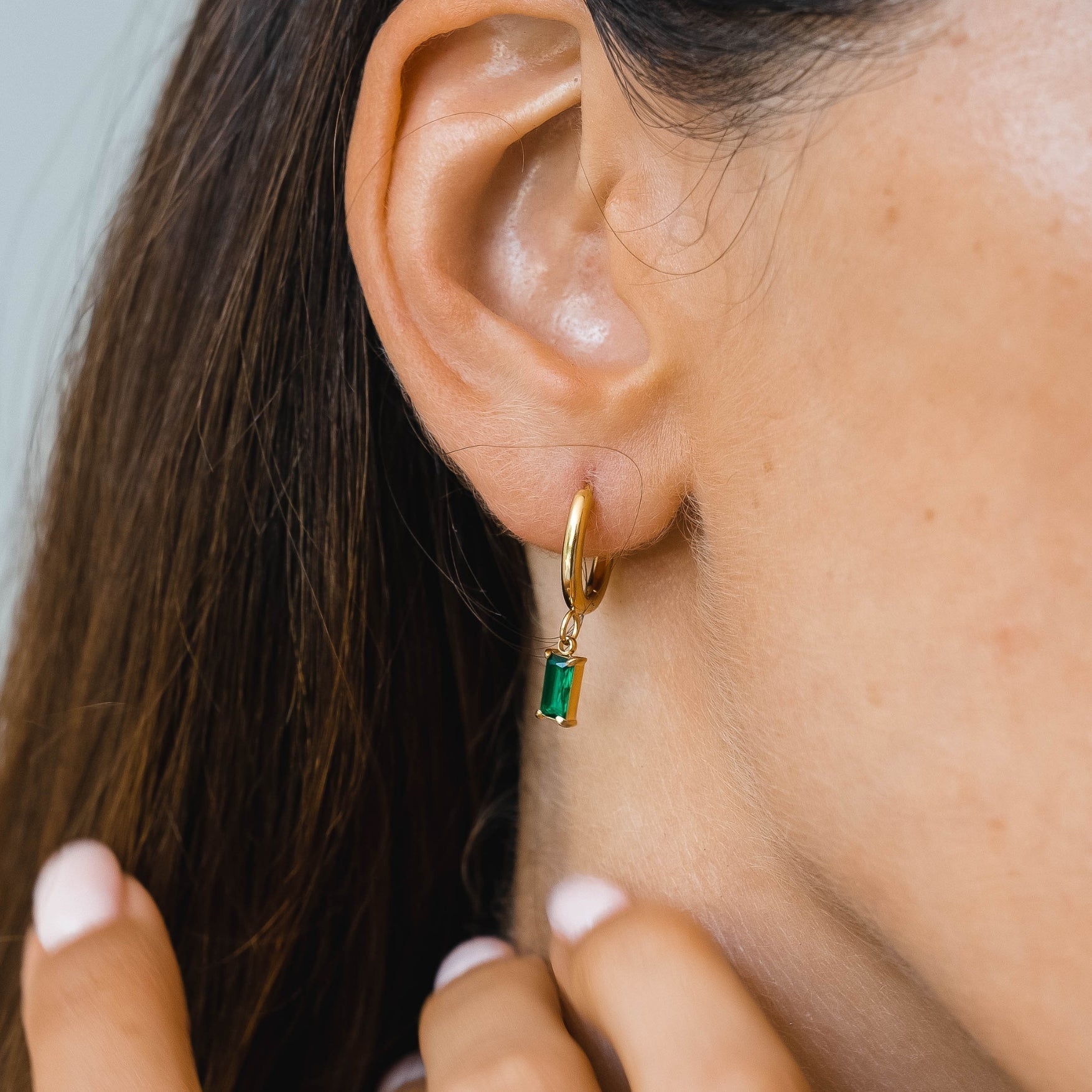 Ohrring mit grünem Stein, goldener Creole, eleganter Schmuck, Damenaccessoire, Nahaufnahme