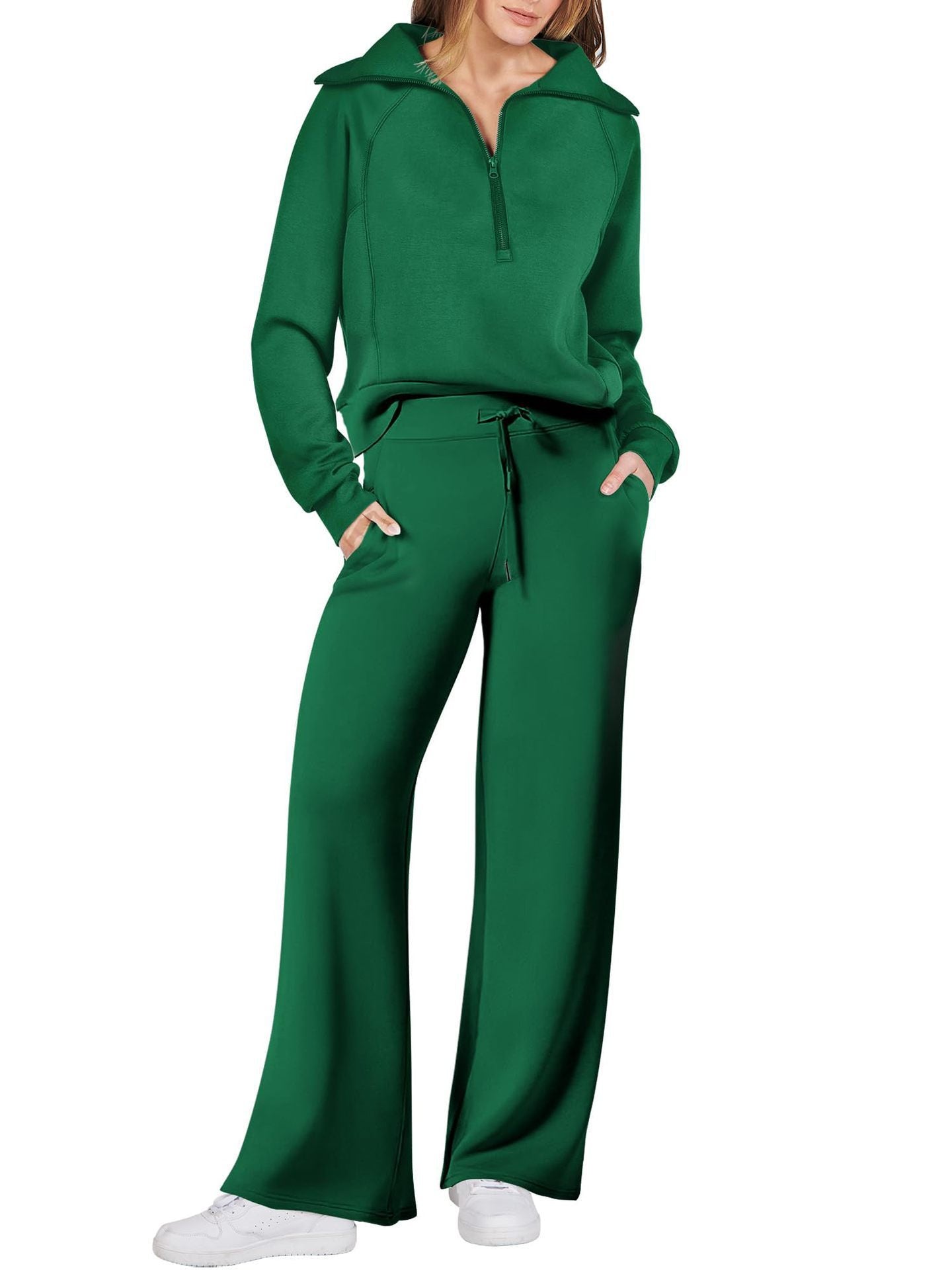 Frau in grünem Jogginganzug, Reißverschluss, weite Hose, Freizeitmode, bequeme Kleidung.