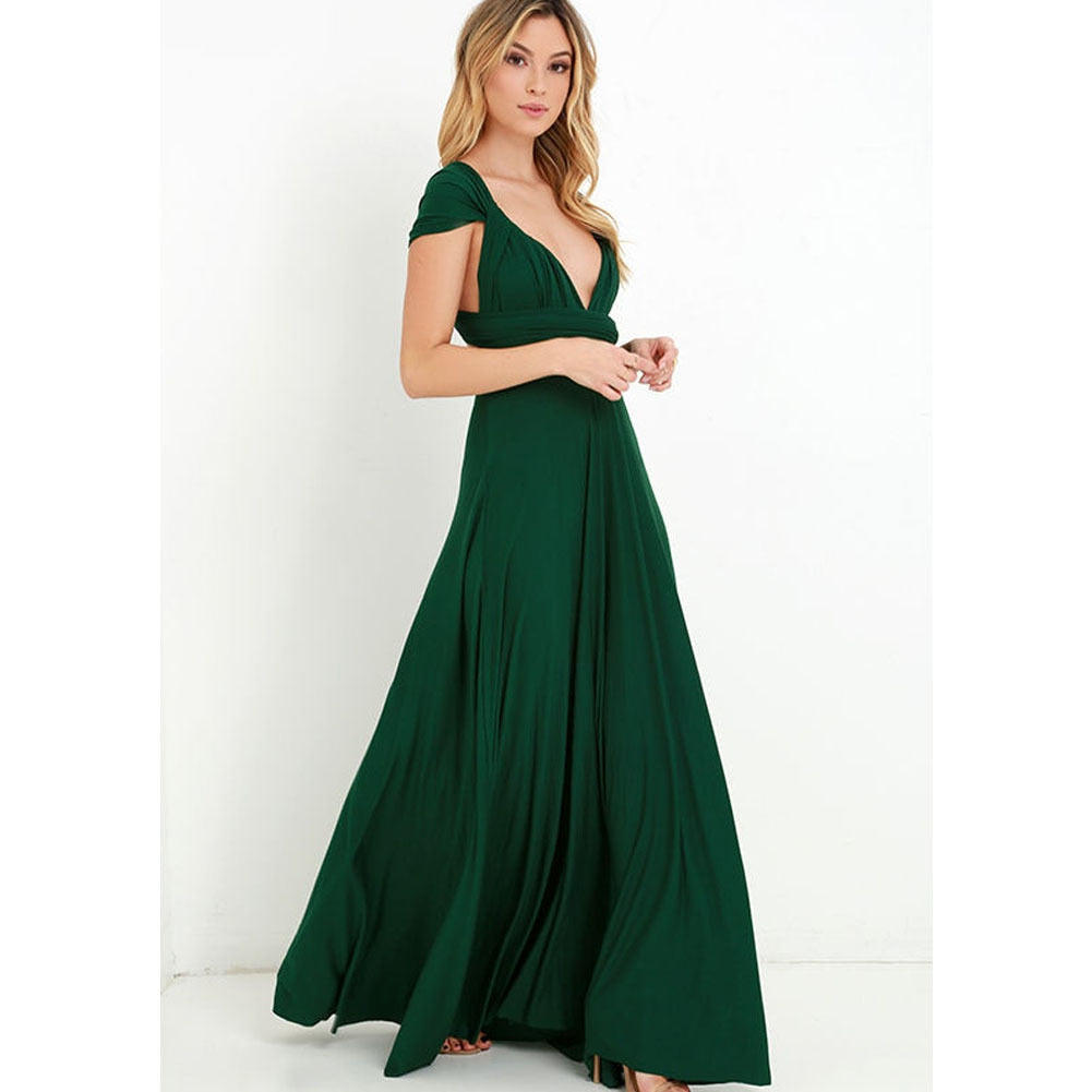 Frau in elegantem, langem, grünem Abendkleid mit tiefem Ausschnitt, stehend vor weißem Hintergrund.