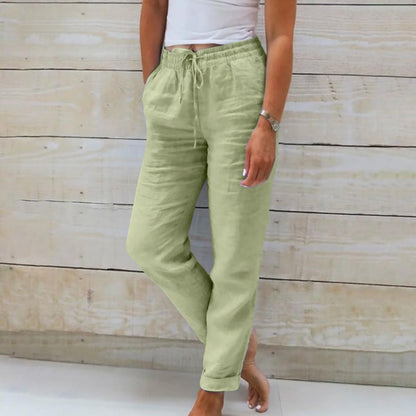 Frau in grüner Leinenhose, weißes Top, Holz-Hintergrund, lässige Sommermode.
