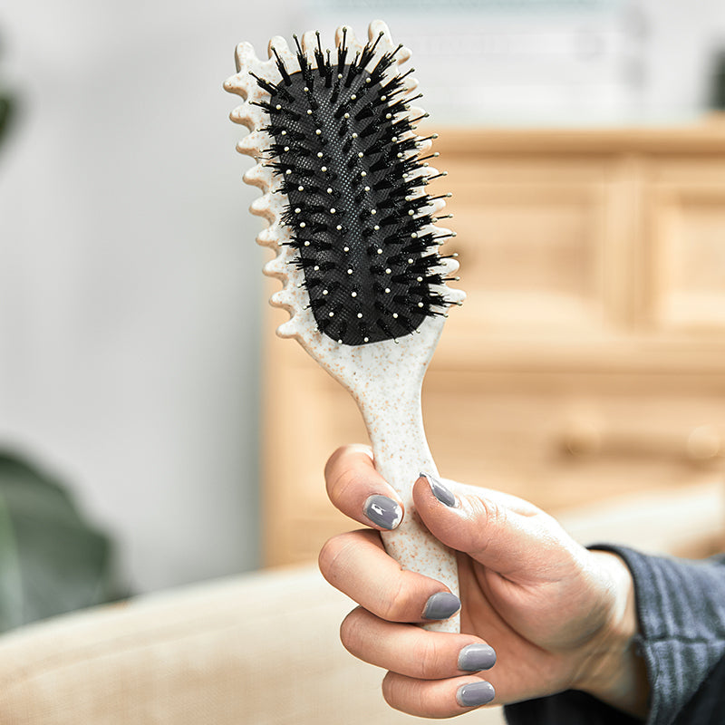 Hand hält weiße Haarbürste mit schwarzen Borsten, ergonomisches Design, für glattes Haarstyling.