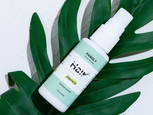 Pansly Haarentfernungsspray, 30ml, weiß-grüne Flasche, auf grünen Blättern, Enthaarungspflege.