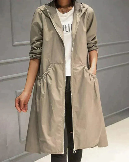 Frau trägt den offenen Regenmantel in Beige mit Kapuze, Reißverschluss und gerafften Eingrifftaschen über weißem Shirt 1