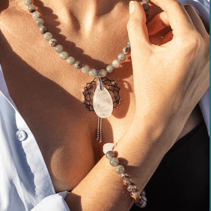 Frau mit Labradorit-Halskette und Armband, weißer Anhänger, eleganter Schmuck, Nahaufnahme.