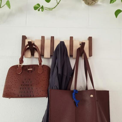 Zweifarbige Holzleiste an weißer Ziegelwand, daran hängen zwei braune Taschen und eine graue Jacke 3