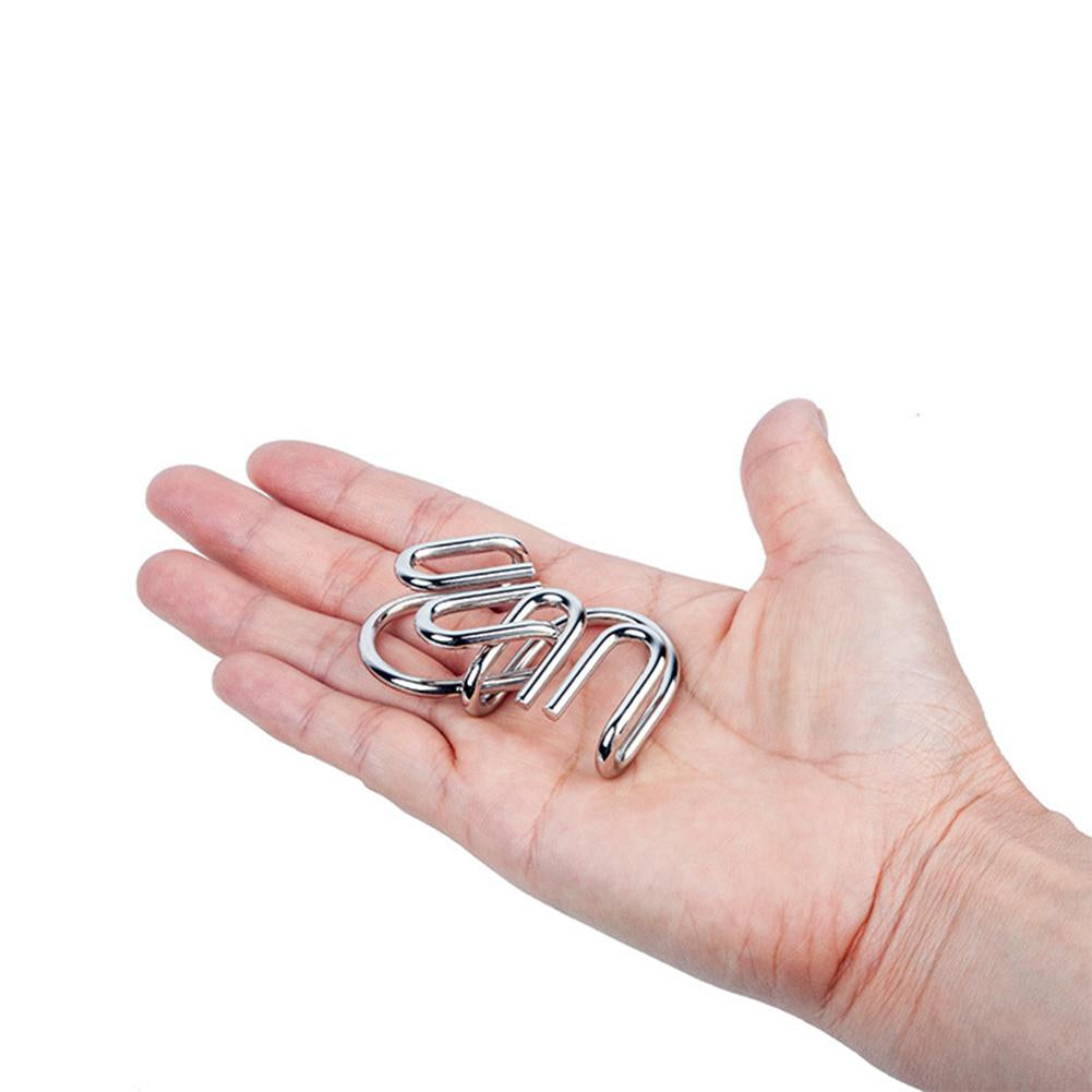 Hand hält silbernes Metallpuzzle, Gehirntraining, Geschicklichkeitsspiel, glänzend, kompakt.