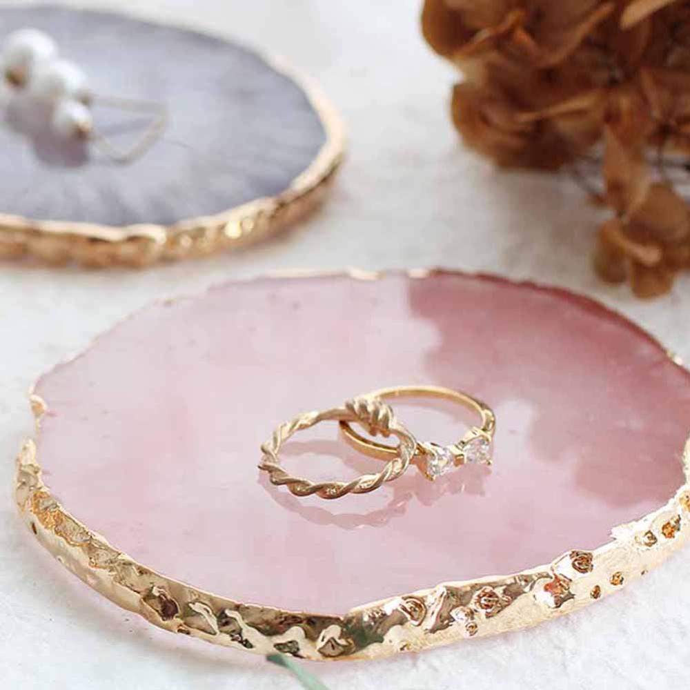 Rosa Harz-Schmuckplatte mit goldenen Ringen, ideal als Organizer für Halsketten und Ohrringe.