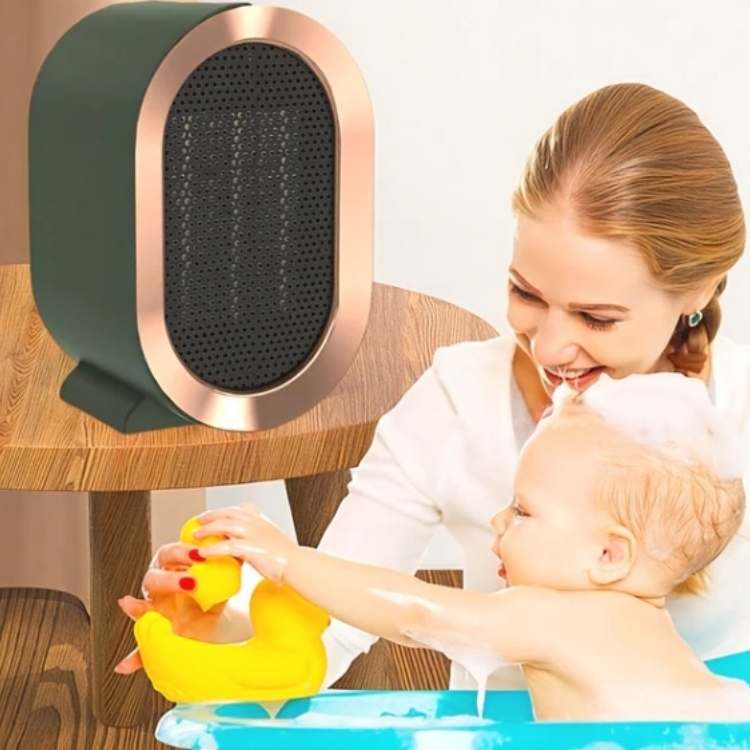 Grüner Heizlüfter auf einem Holztisch, daneben lächelt eine Frau ihr badendes Baby mit Gummiente an 3