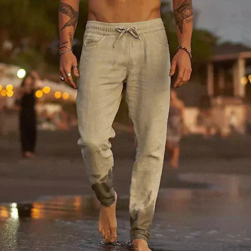 Mann in beigen Jogginghosen am Strand bei Sonnenuntergang, lässige Freizeitmode.