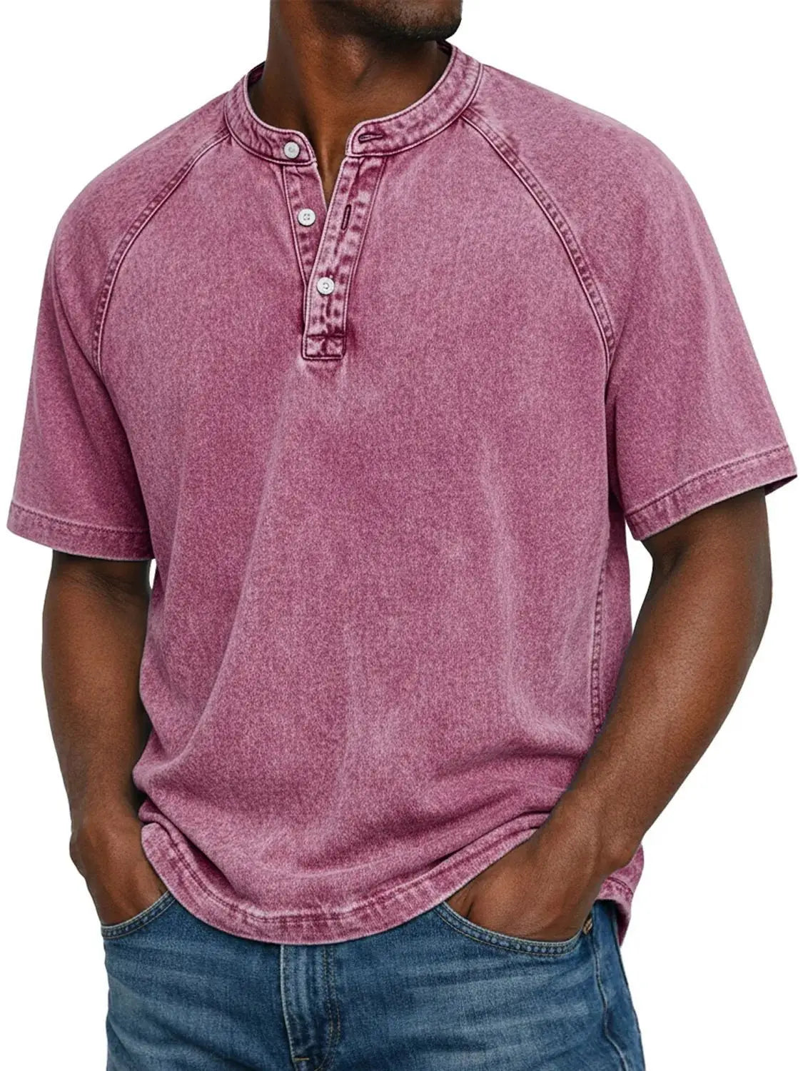 Mann trägt das ausgewaschene Henley-Shirt mit Raglanärmeln in Beerenrosa, Frontansicht mit Knopfleiste und Jeans. 10