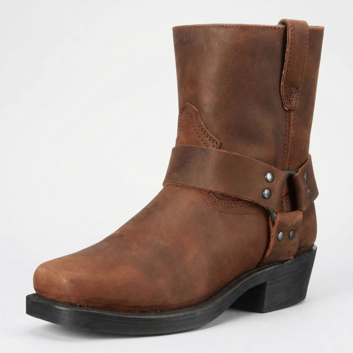 Brauner Lederstiefel mit Riemen, Nieten und eckiger Spitze in Dreiviertelansicht von vorne auf hellgrauem Hintergrund. 2
