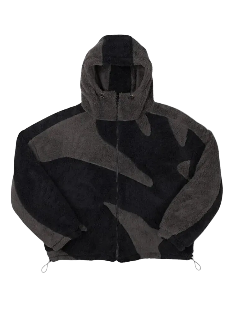 Flauschige Fleecejacke in Schwarz und Dunkelgrau mit großflächigem Segmentmuster, Kapuze und Reißverschluss, von vorne auf weißem Hintergrund. 1