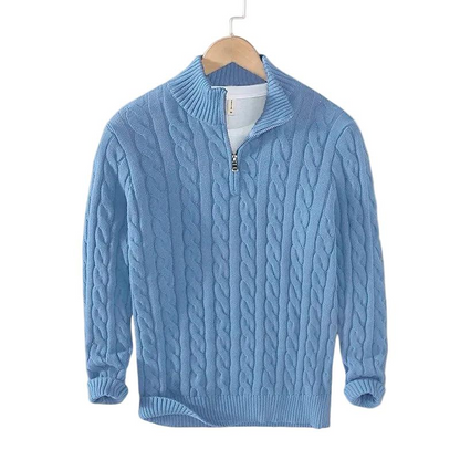 Hellblauer Zopfstrick-Pullover mit Stehkragen und kurzem Reißverschluss, auf einem Bügel hängend, mit weißem Shirt darunter. 3