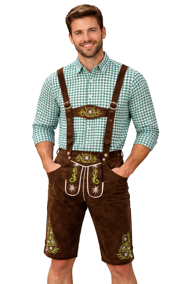 Lächelnder Mann in brauner Lederhose mit grün bestickten Edelweiß-Motiven und grün-weiß kariertem Hemd, vor weißem Hintergrund freigestellt. 1