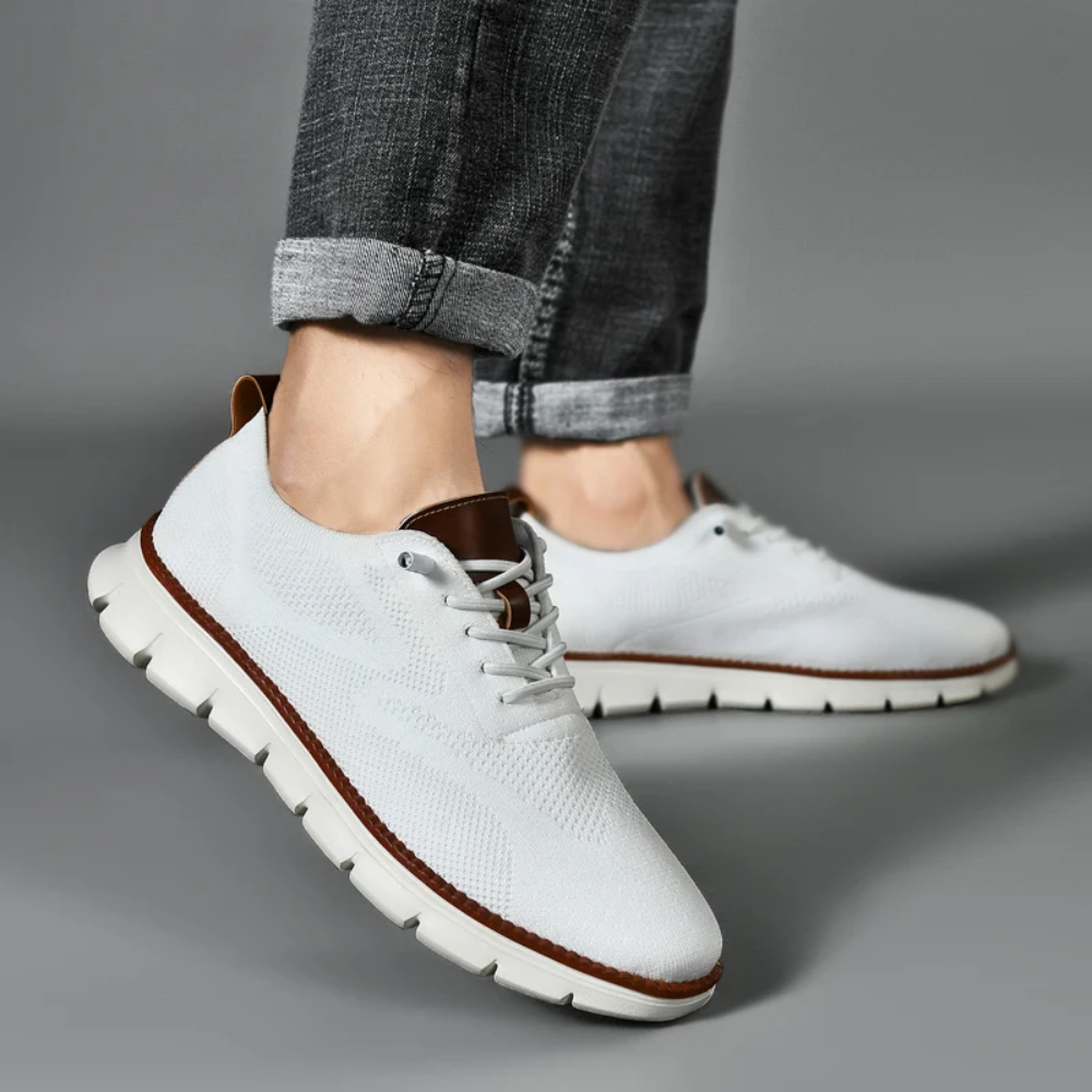 Weiße Herren-Sneaker aus Leder, sportlich, bequem, mit braunen Akzenten, auf grauem Hintergrund.
