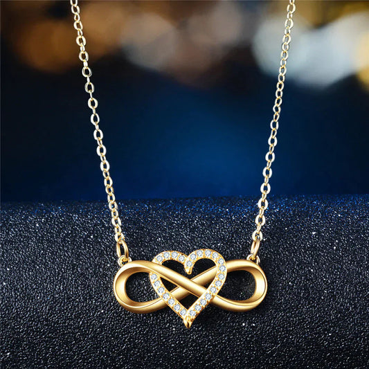 Goldene Halskette mit Herz- und Unendlichkeitsanhänger, verziert mit Kristallen, eleganter Schmuck.