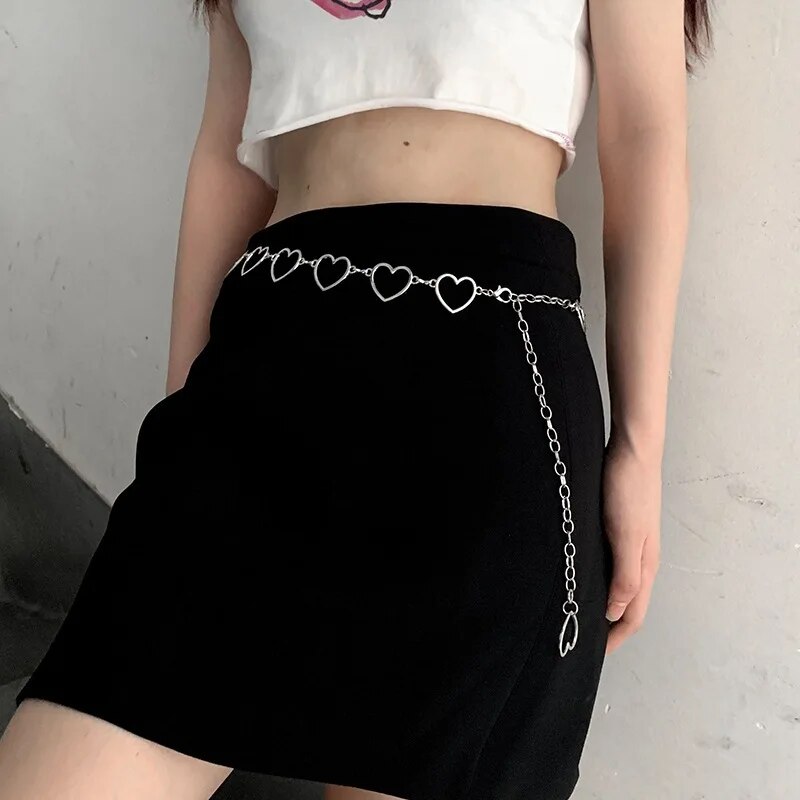 Frau mit schwarzem Rock und silberner Herz-Kettengürtel, modisches Accessoire, trendig.