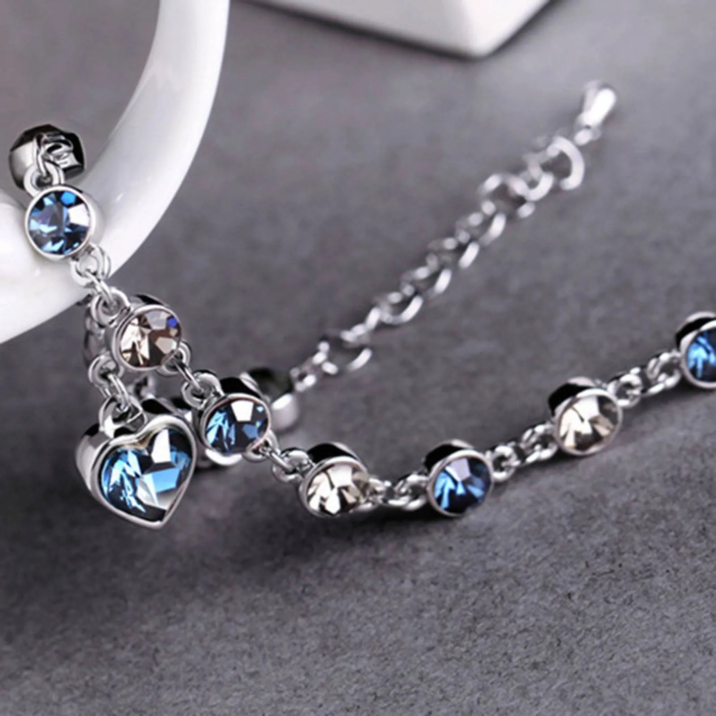 Silberarmband mit blauen und klaren Kristallen, Herzanhänger, eleganter Schmuck für Damen.
