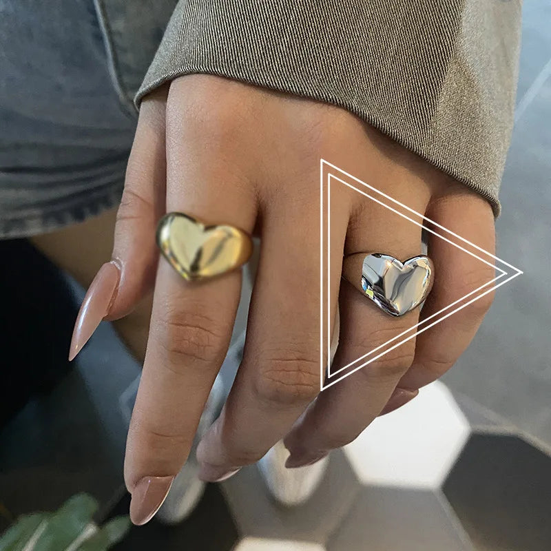 Herzförmige Ringe in Gold und Silber an Hand, modischer Schmuck, Nahaufnahme.