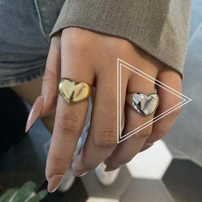 Herzförmige Ringe in Gold und Silber an Hand, modischer Schmuck, Nahaufnahme.