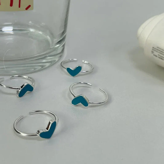 Silberne Ringe mit blauen Herzmotiven auf grauem Hintergrund, Schmuckaccessoires.