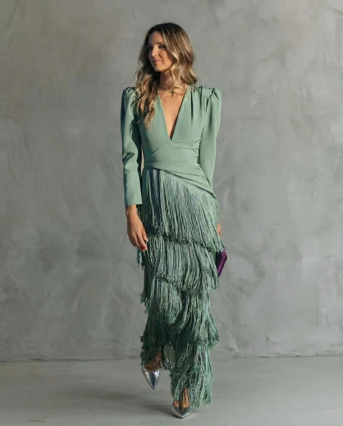 Frau in grünem Fransenkleid mit Puffärmeln, Ganzkörperansicht von vorn, mit lila Clutch und silbernen Pumps 2
