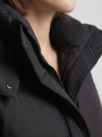 Detailaufnahme von Stehkragen, Reißverschluss und Druckknopf der schwarzen Steppjacke, am Model 7
