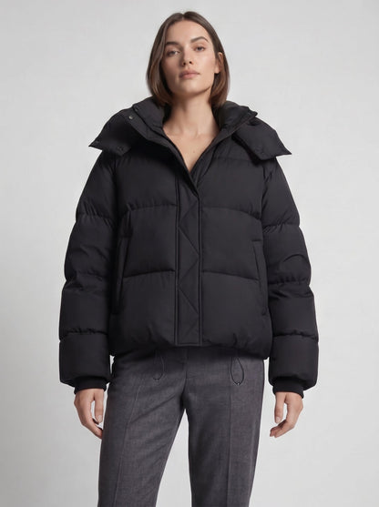 Model in schwarzer, oversized Steppjacke mit hochgestelltem Kragen und grauer Hose, Frontansicht ab Taille 6