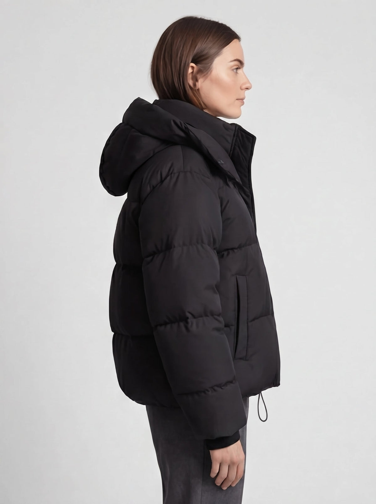 Seitenansicht der schwarzen Steppjacke am Model, Kapuze, Eingrifftasche und Kordelzug am Saum sichtbar 5