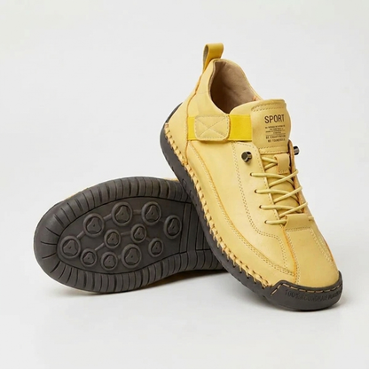 Gelber Sneaker mit gelbem Elastikband und dunkler Sohle, ein zweiter Schuh liegt mit dem Sohlenprofil nach oben. 13