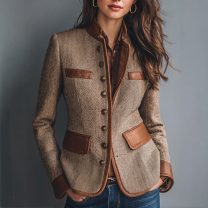 Frontansicht der beigebraunen Fischgrät-Jacke mit cognacfarbenem Besatz und Metallknöpfen, getragen mit Jeans und brauner Bluse vor grauem Hintergrund. 1