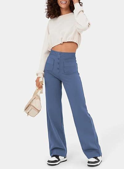 Frau in blauer, hoch taillierter, elastischer Hose und weißem Pullover, lässiger Stil.