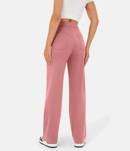 Frau trägt rosa hoch taillierte elastische Freizeithose, Rückansicht, weiße Sneakers.