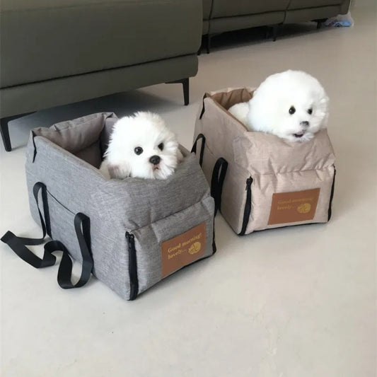 Zwei weiße Hunde in grauen und beigen Hundetragetaschen auf hellem Boden.
