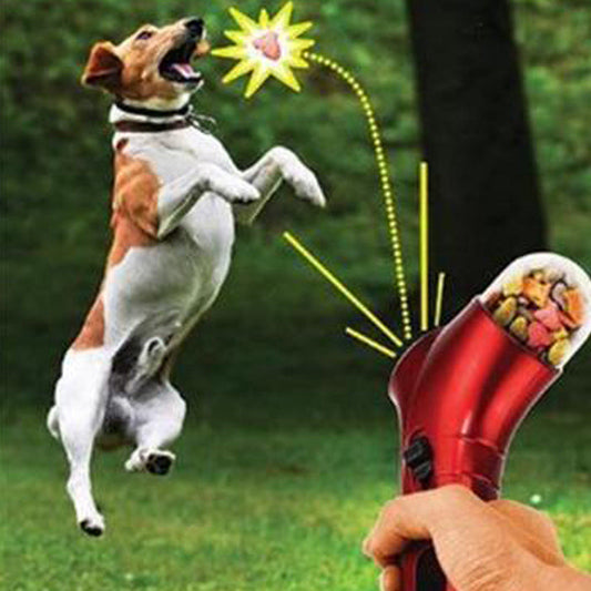 Hund springt nach Leckerli aus rotem Futterwerfer im Park, interaktives Hundespielzeug.