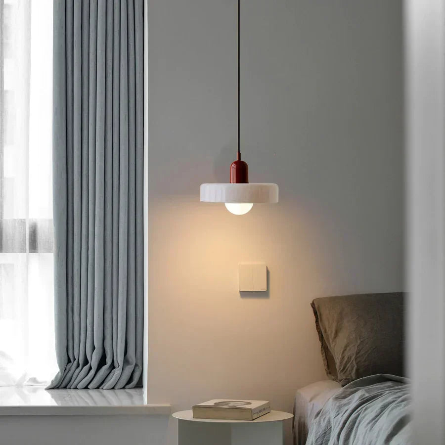 Moderne rote Hängelampe über Nachttisch in minimalistischem Schlafzimmer, graue Vorhänge.