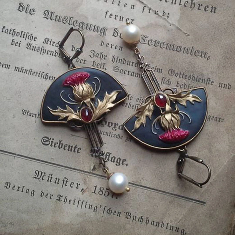 Antike Ohrringe mit rotem Edelstein und Perlen, florales Design, auf altem Buch, Vintage-Schmuck.