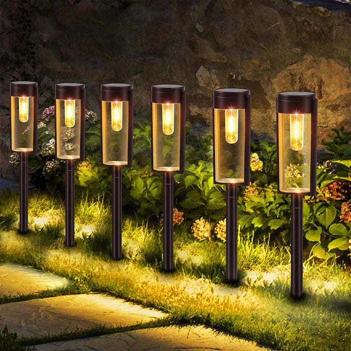Sechs schwarze Solar-Gartenleuchten beleuchten einen Weg bei Nacht.