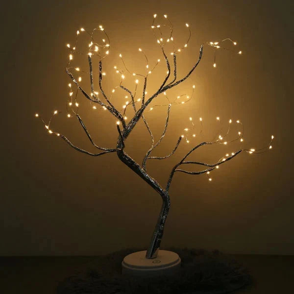 Lichterbaum mit weit verzweigten, gebogenen Ästen und Lichtern vor schlichter, warm beleuchteter Wand 4