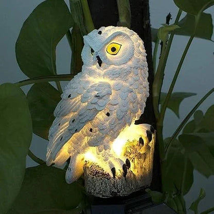 Nahaufnahme einer weiß leuchtenden Eule mit gelben Augen, die vor großen grünen Blättern warmes Licht abgibt. 8