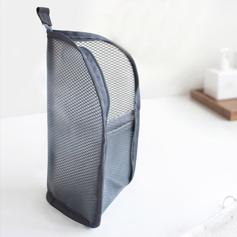 Graue Netztasche steht aufrecht auf einer weißen Fläche, mit Tragschlaufe oben und Außenfach an der Seite. 7