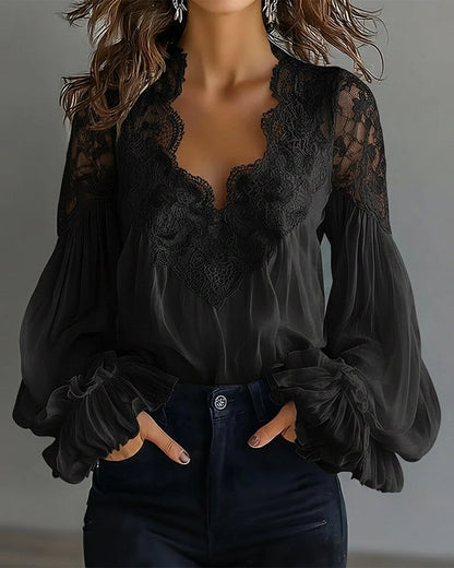 Schwarze Bluse mit Spitzenausschnitt und Rüschenmanschetten, Model mit Händen in den Hosentaschen 6