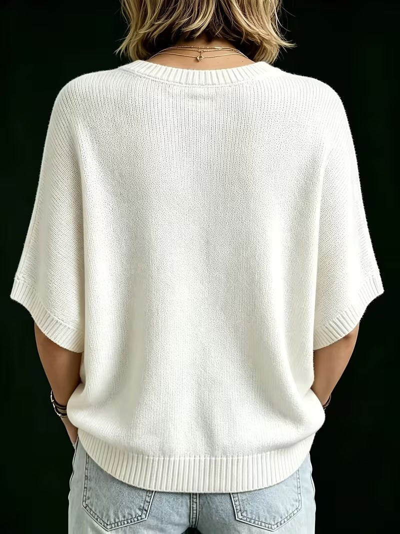 Rückansicht des cremeweißen Strickoberteils mit Rundhalsausschnitt, weiten Fledermausärmeln und geripptem Saum, kombiniert mit heller Jeans. 25